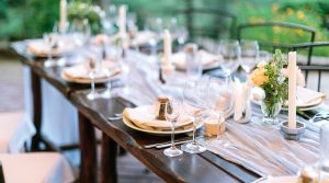 fest, dinner, tradition concept. long oaken table served for celebration with silverware, dishes and transparent dazzling glasses, flowers and candles in interesting holders in form of octagonal